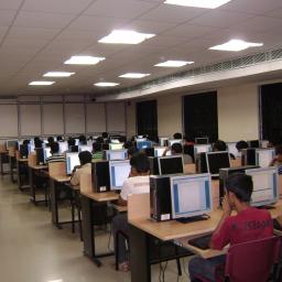 A number of individual students behind computer screens in a class room.